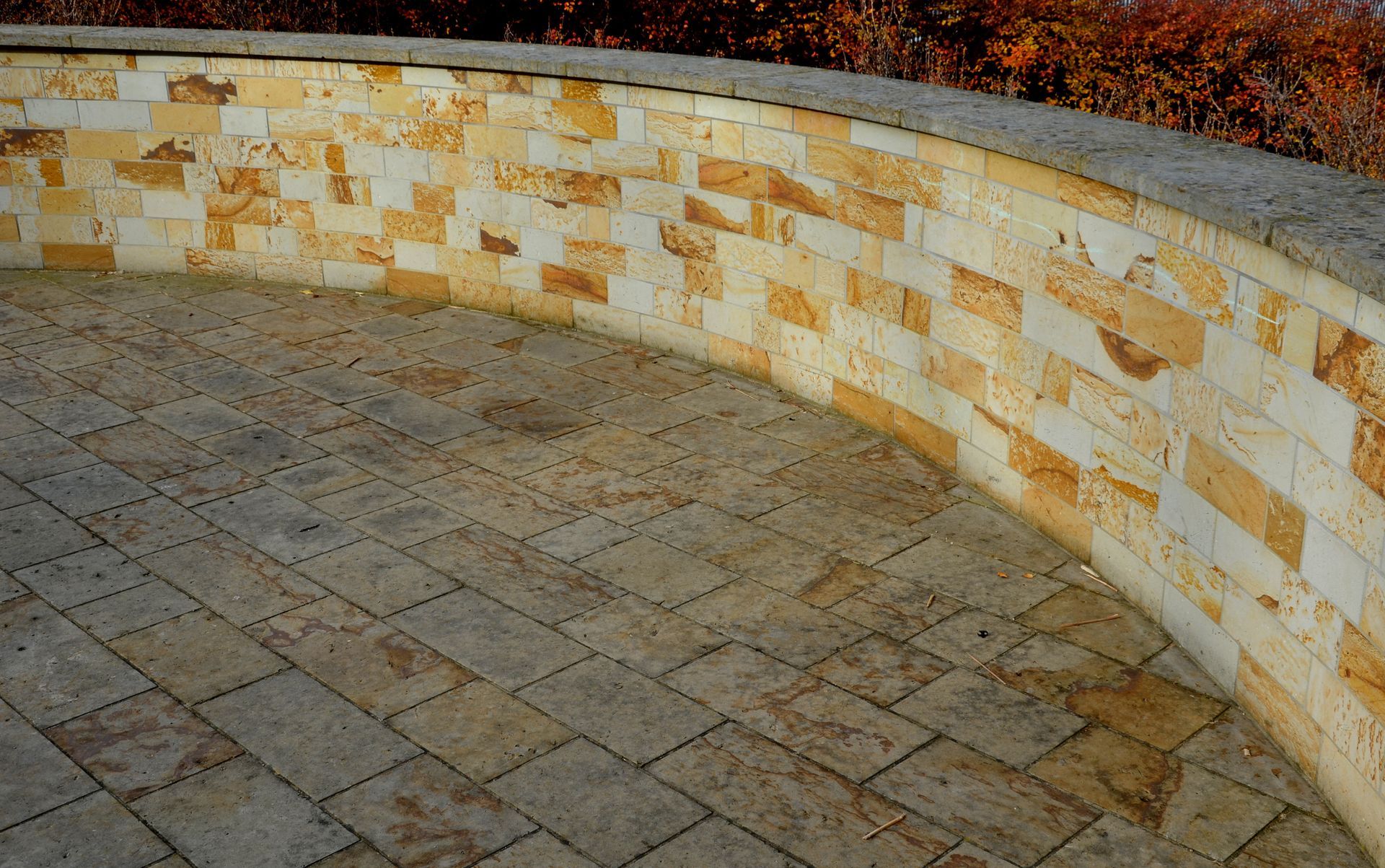 Curved sandstone brick wall and matching ground, outdoor setting. Curved sandstone brick wall and matching ground, outdoor setting.