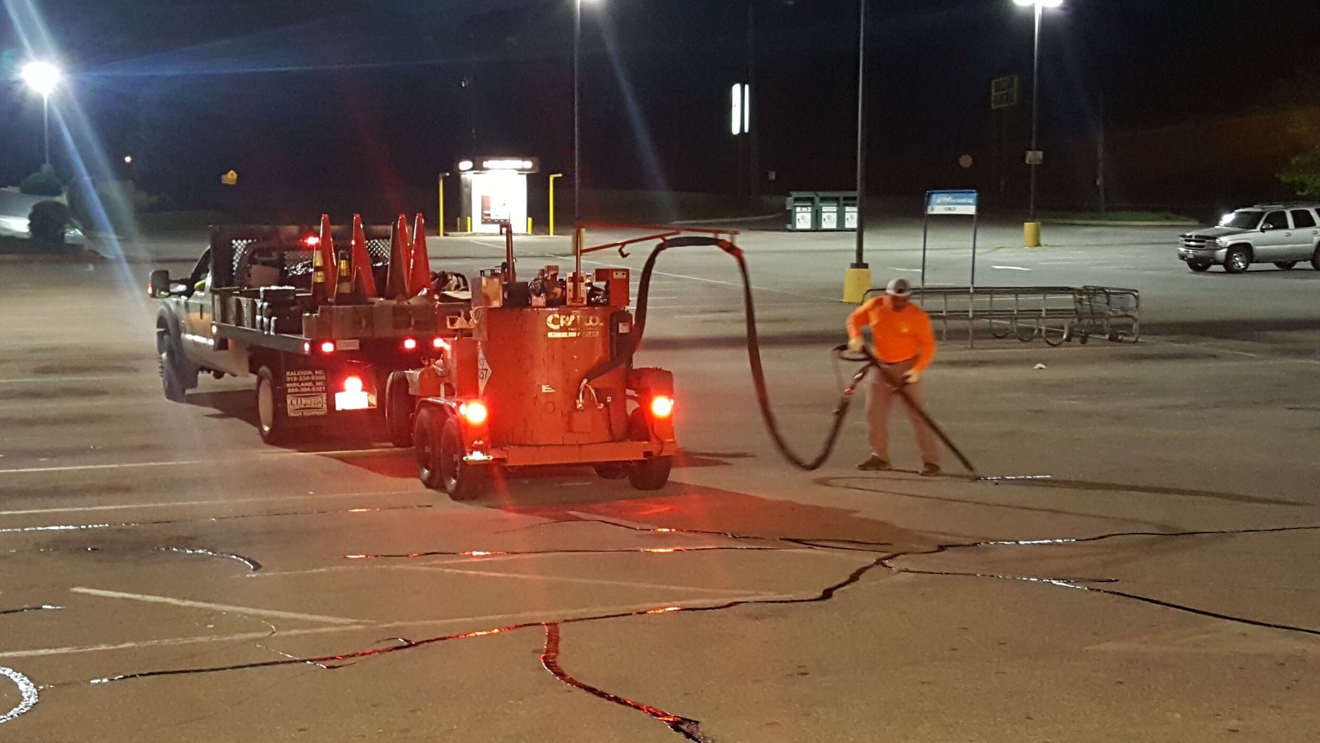 A man is standing next to a truck in a parking lot at night.