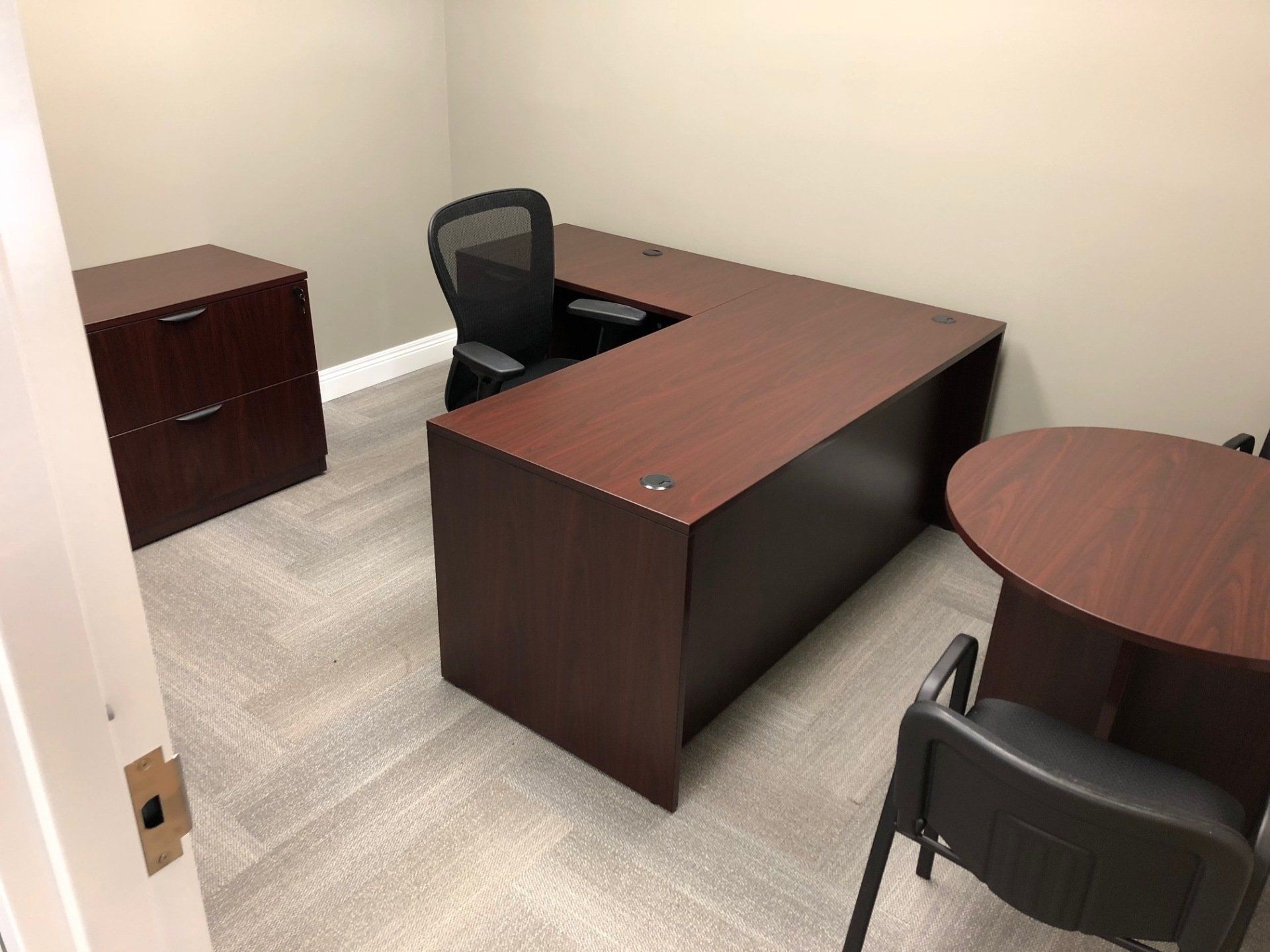 A small office with a desk , chair , and filing cabinet.