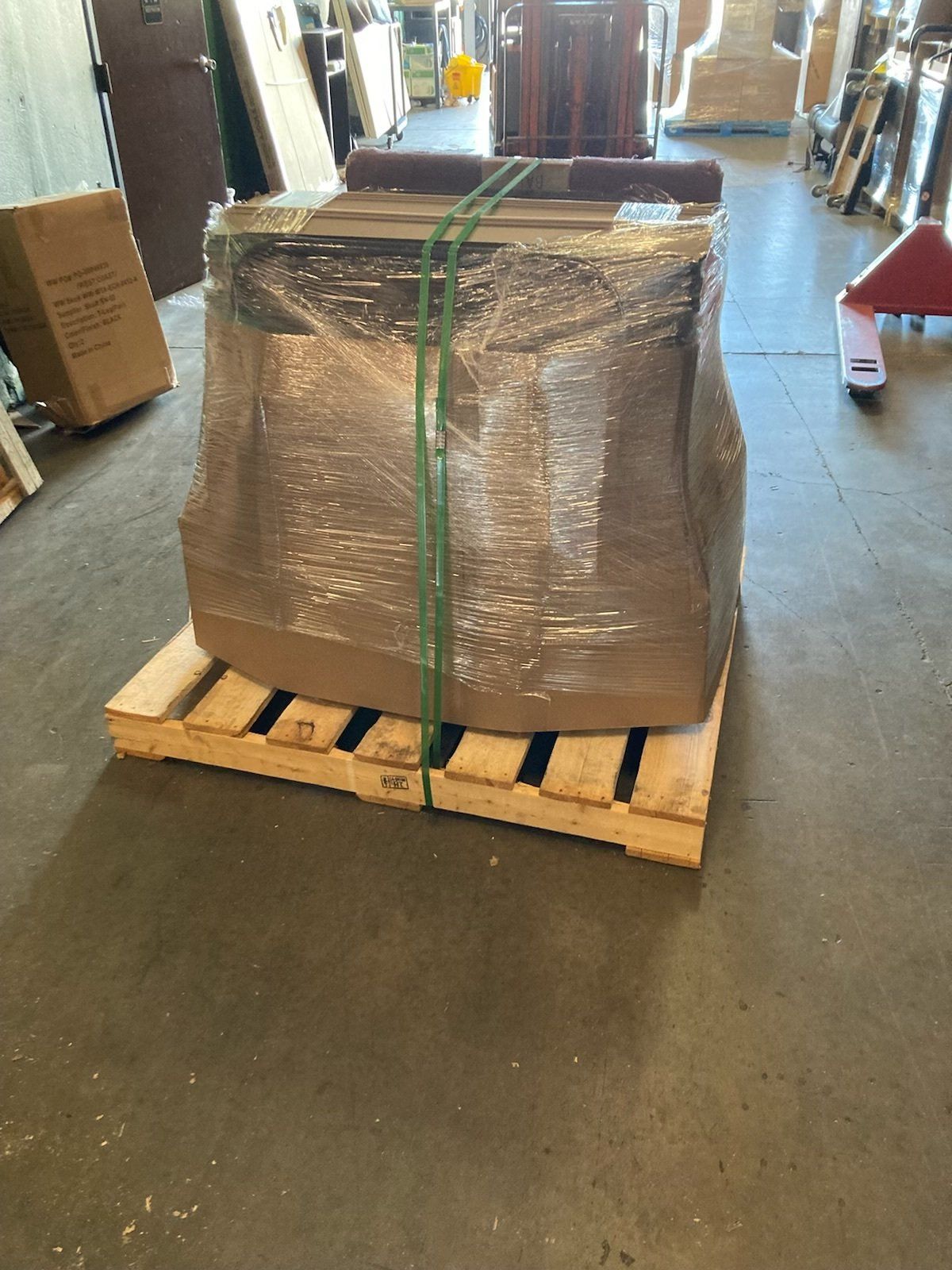 A large box wrapped in plastic is sitting on a wooden pallet.