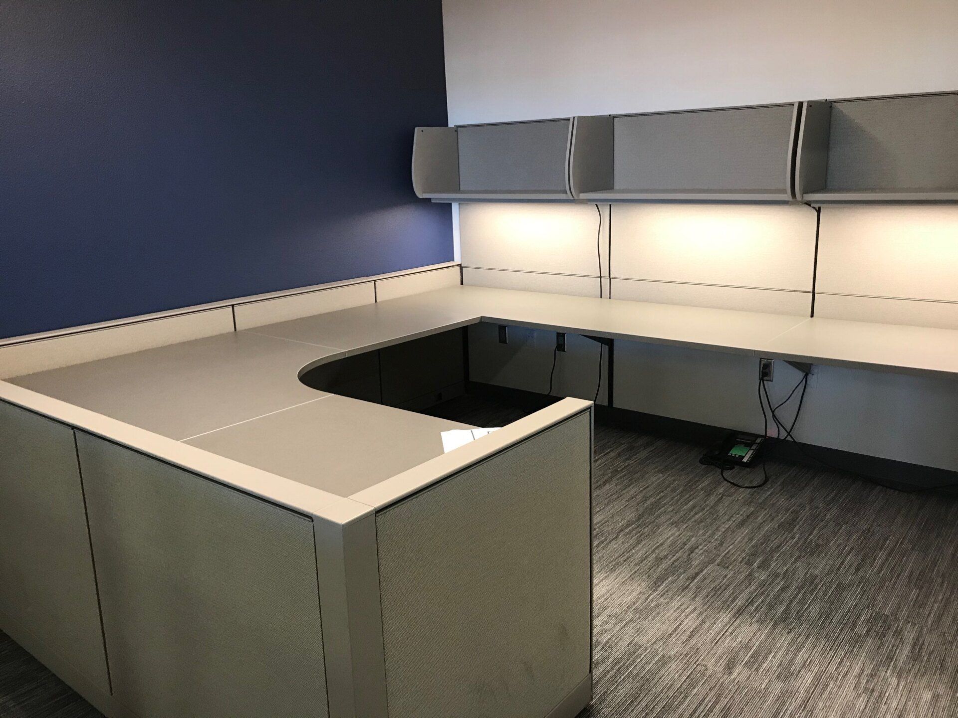 A cubicle with a desk and a blue wall