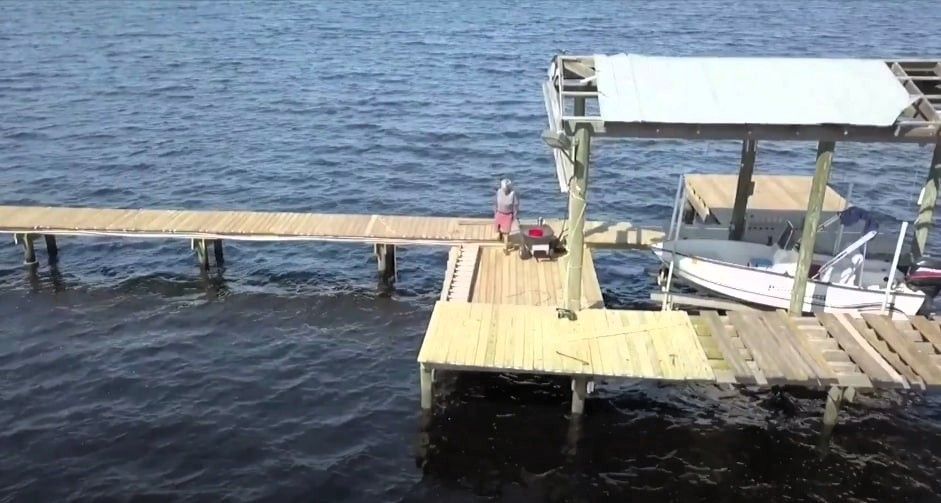 Person on wooden dock inspecting for boat dock repairs needed