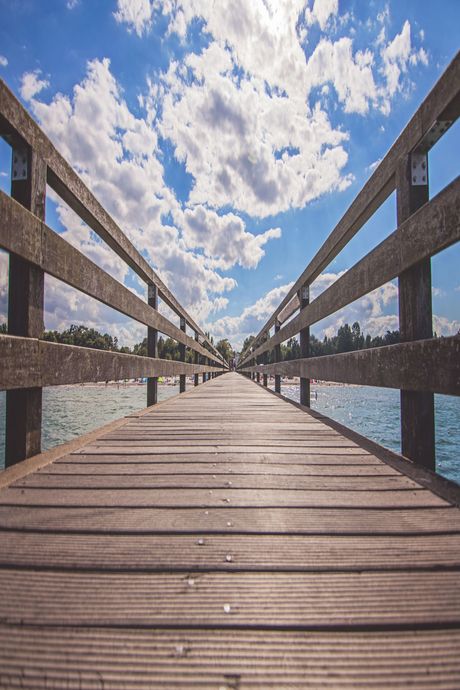 A wooden pier leading to a body of water on a sunny day.