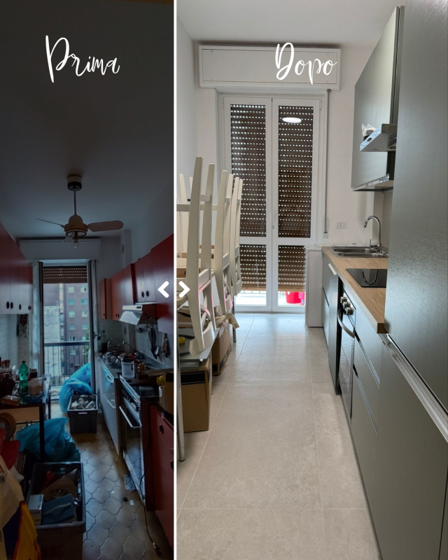 Vista divisa tra una sala da pranzo buia e una cucina luminosa e stretta con mobili bianchi e porta a vetri.