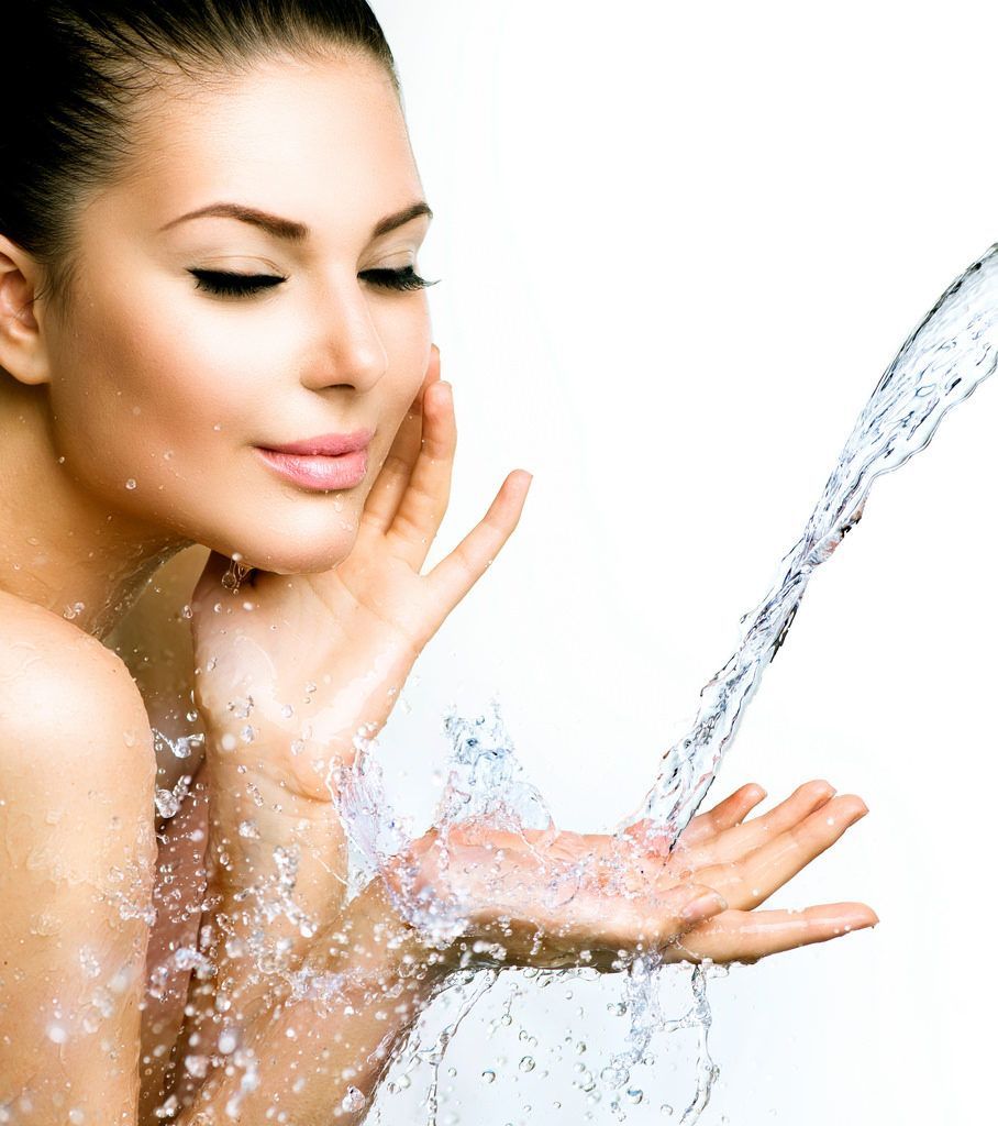 Woman washing her face with water splashing from a stream