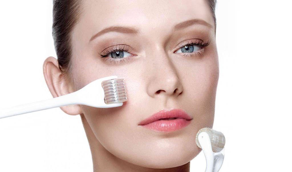 Woman with facial roller and serum applicator applied to her cheek in a beauty treatment close-up