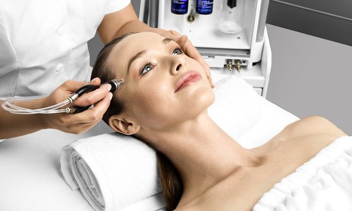 Woman receiving a facial treatment with a brush while lying on a spa bed