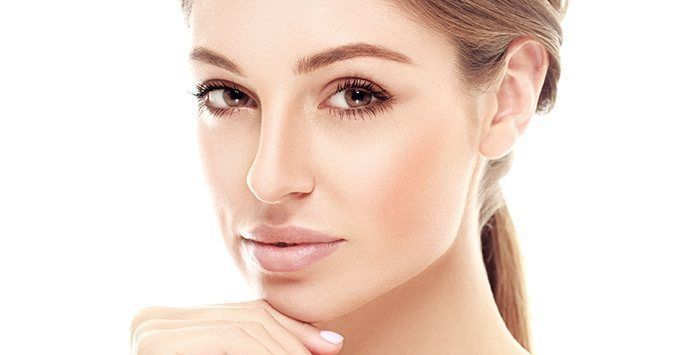 Close-up portrait of a person with light makeup, looking at the camera with a neutral expression.