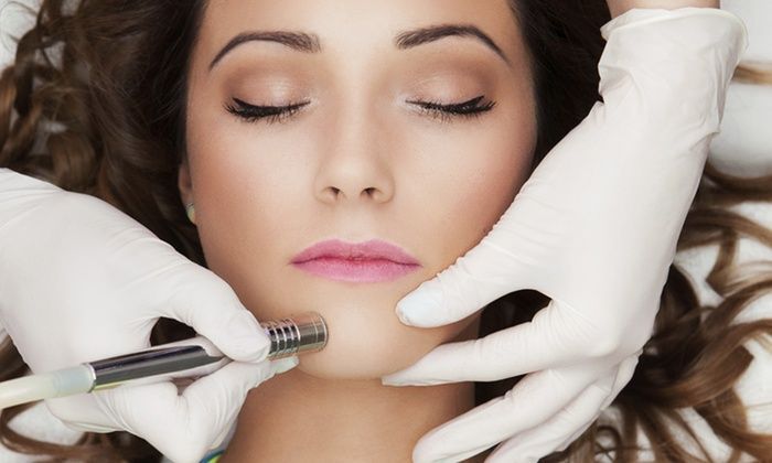 Gloved hands administer a facial injection to a reclining woman with eyes closed