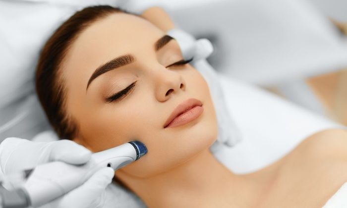 Facial treatment being applied to a woman lying on a spa bed, using a handheld device
