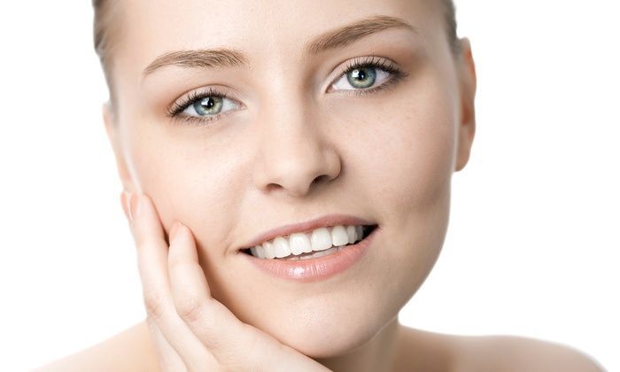 Close-up of a smiling person with hand on cheek against a white background