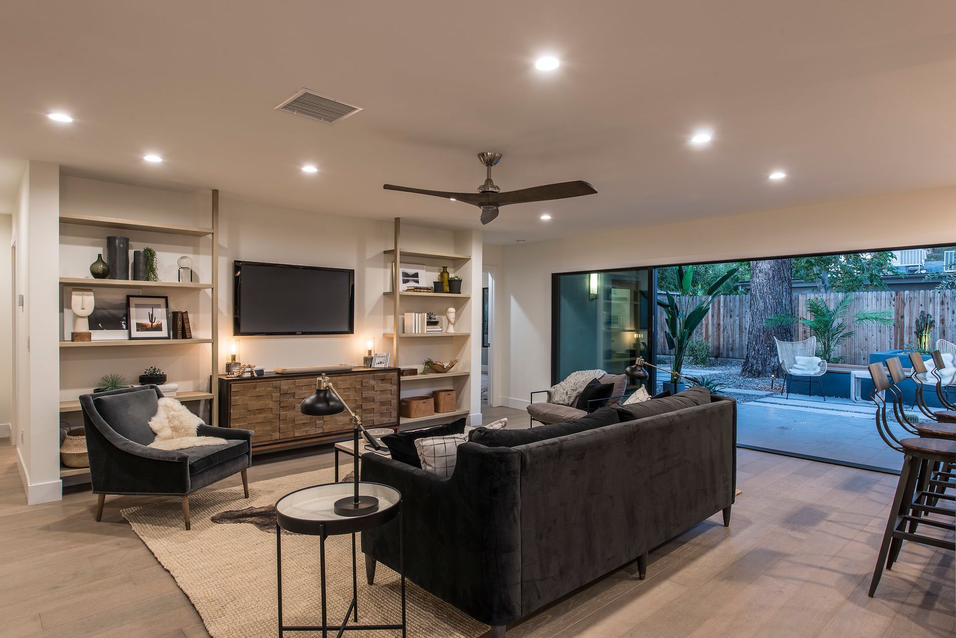 A living room with a couch , chairs , a television and a ceiling fan.