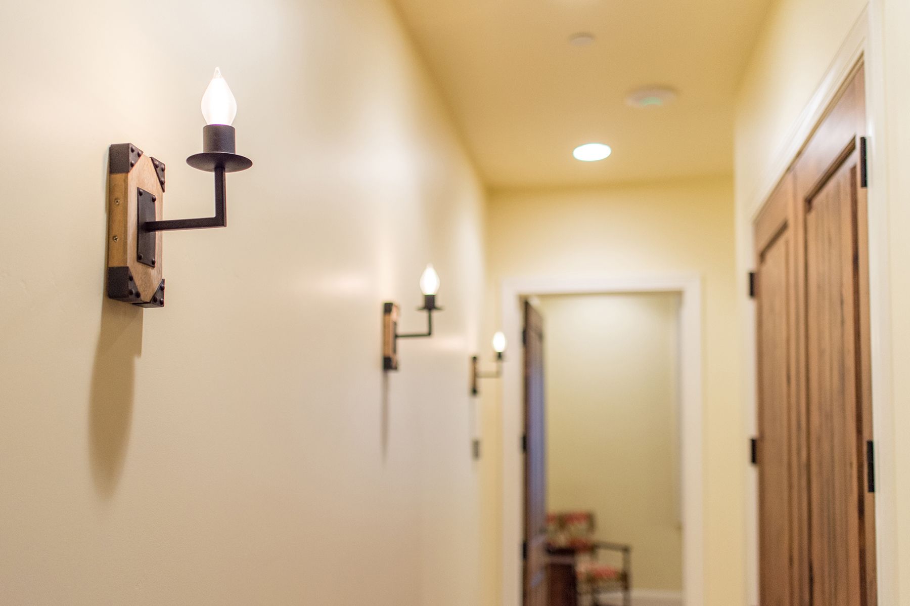 A hallway with two lights on the wall and a chair in the background.