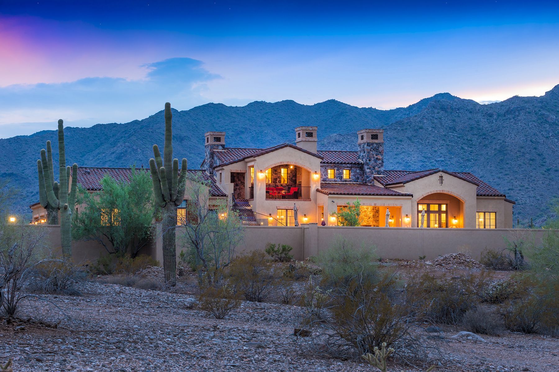 A large house in the desert with mountains in the background.