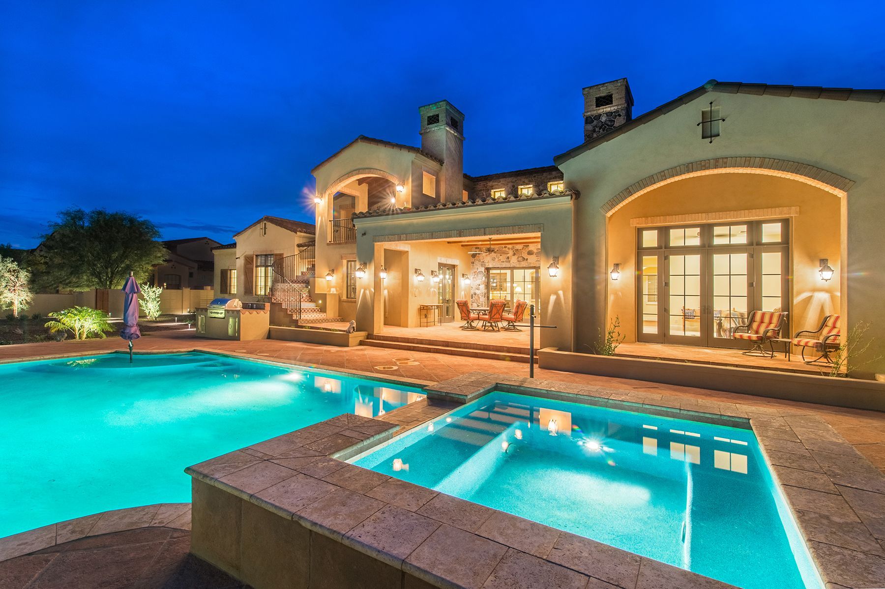 A large house with a swimming pool and a hot tub in front of it.