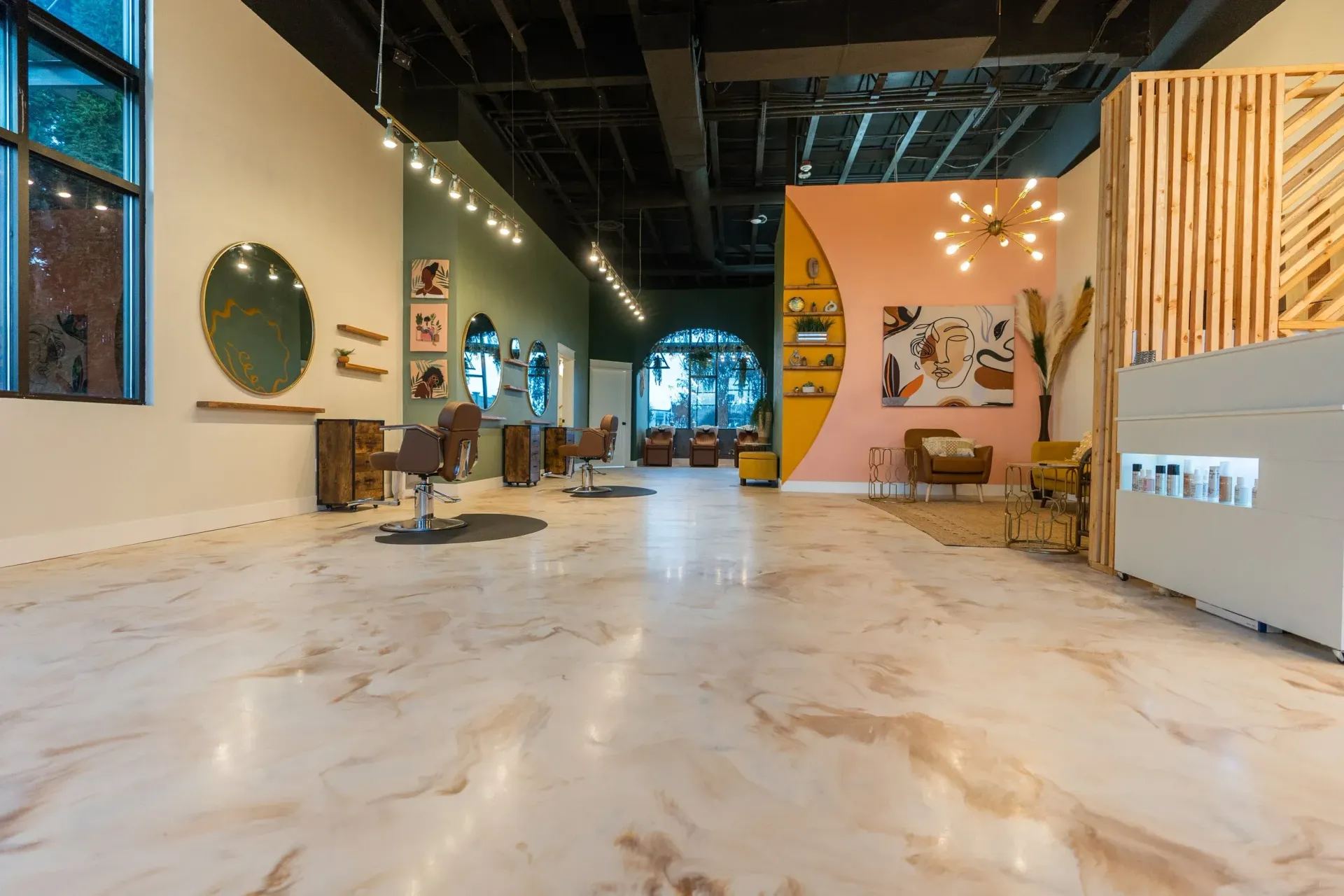Salon interior: gold-veined floor, pink and green walls, mirrors, styling chairs, decorative lighting, and a wood accent.
