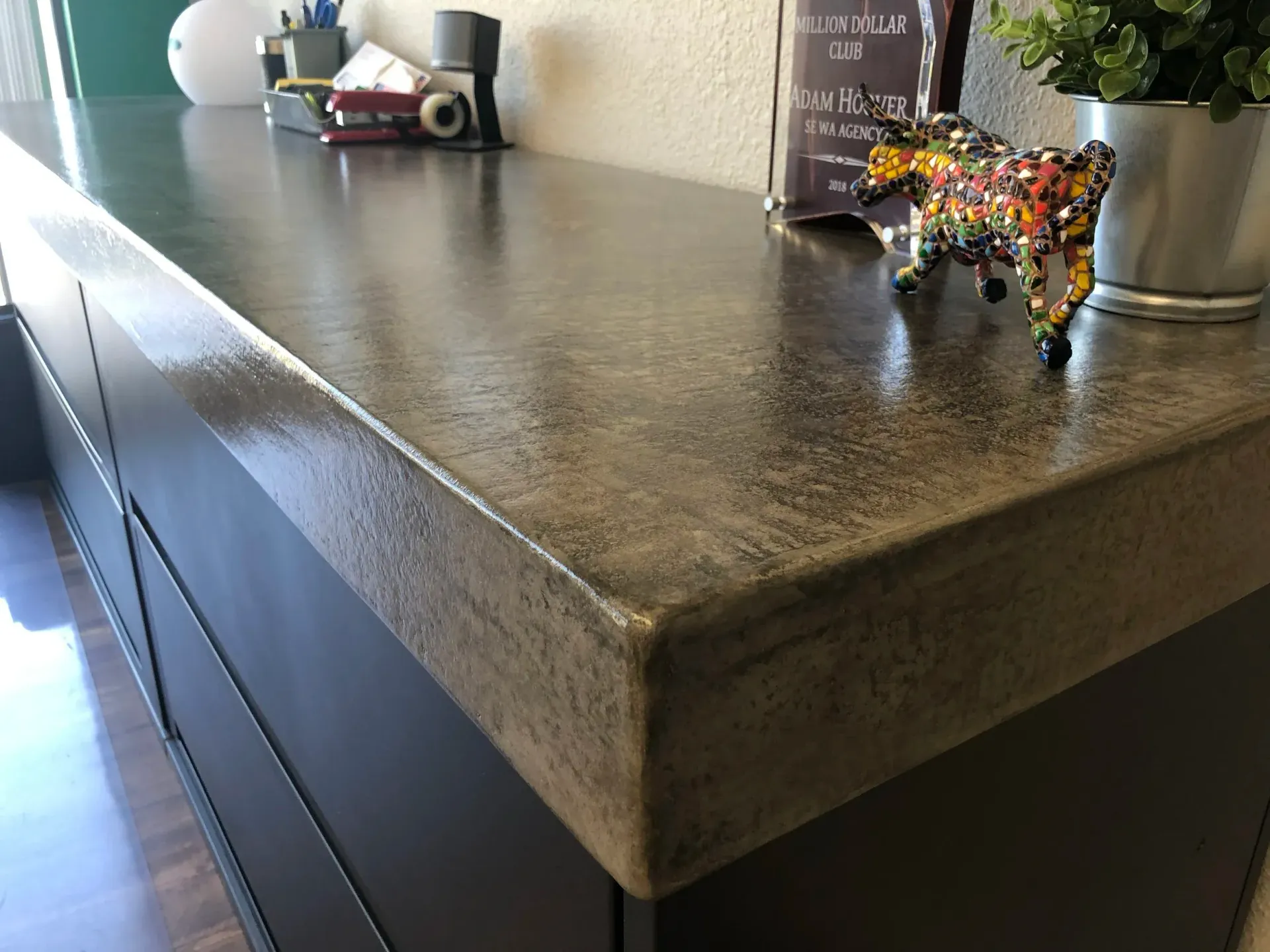 A dark cabinet with a shiny, speckled countertop, adorned with office supplies and decorative items.