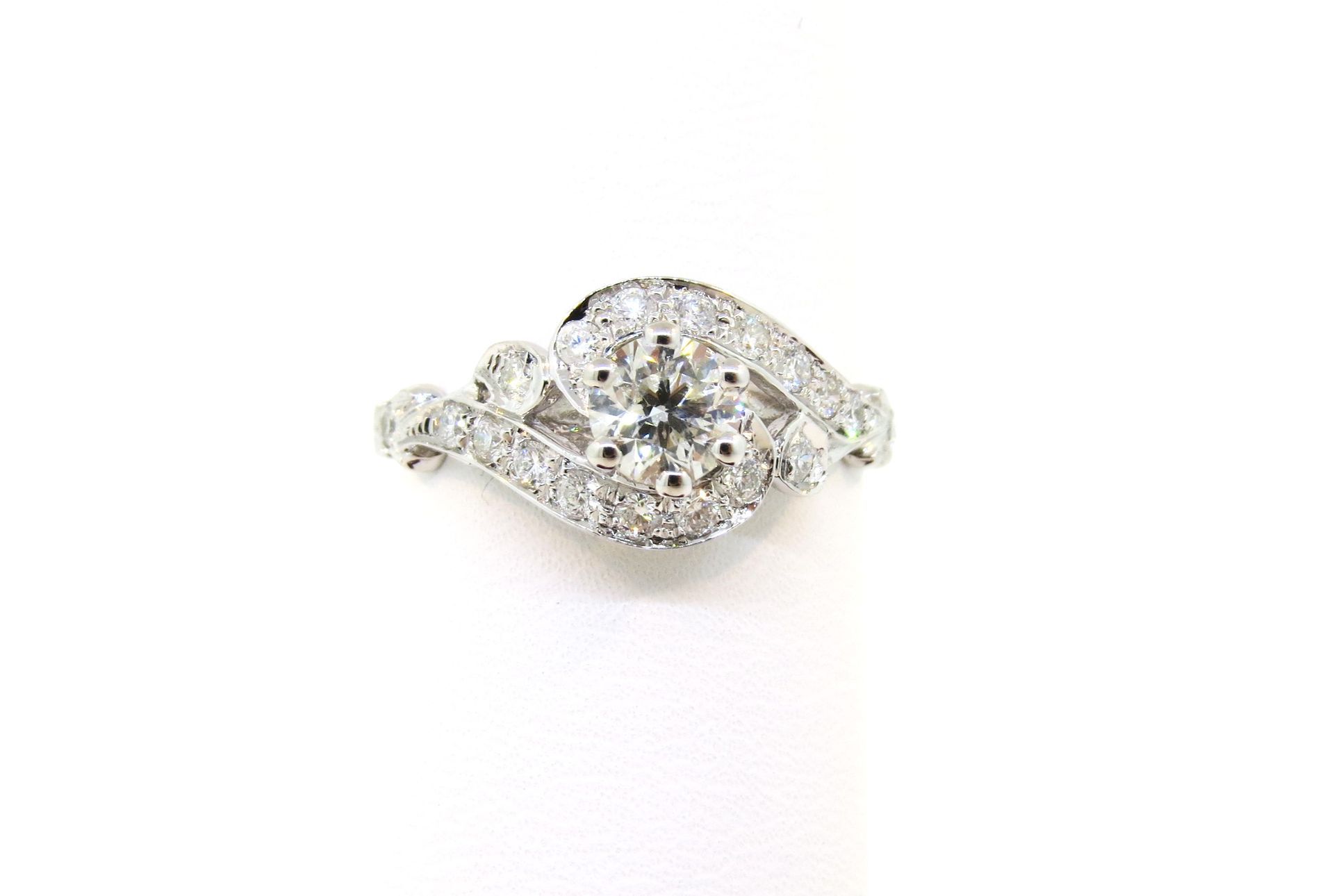 Silver diamond ring with a central round stone and floral cluster details on a white background