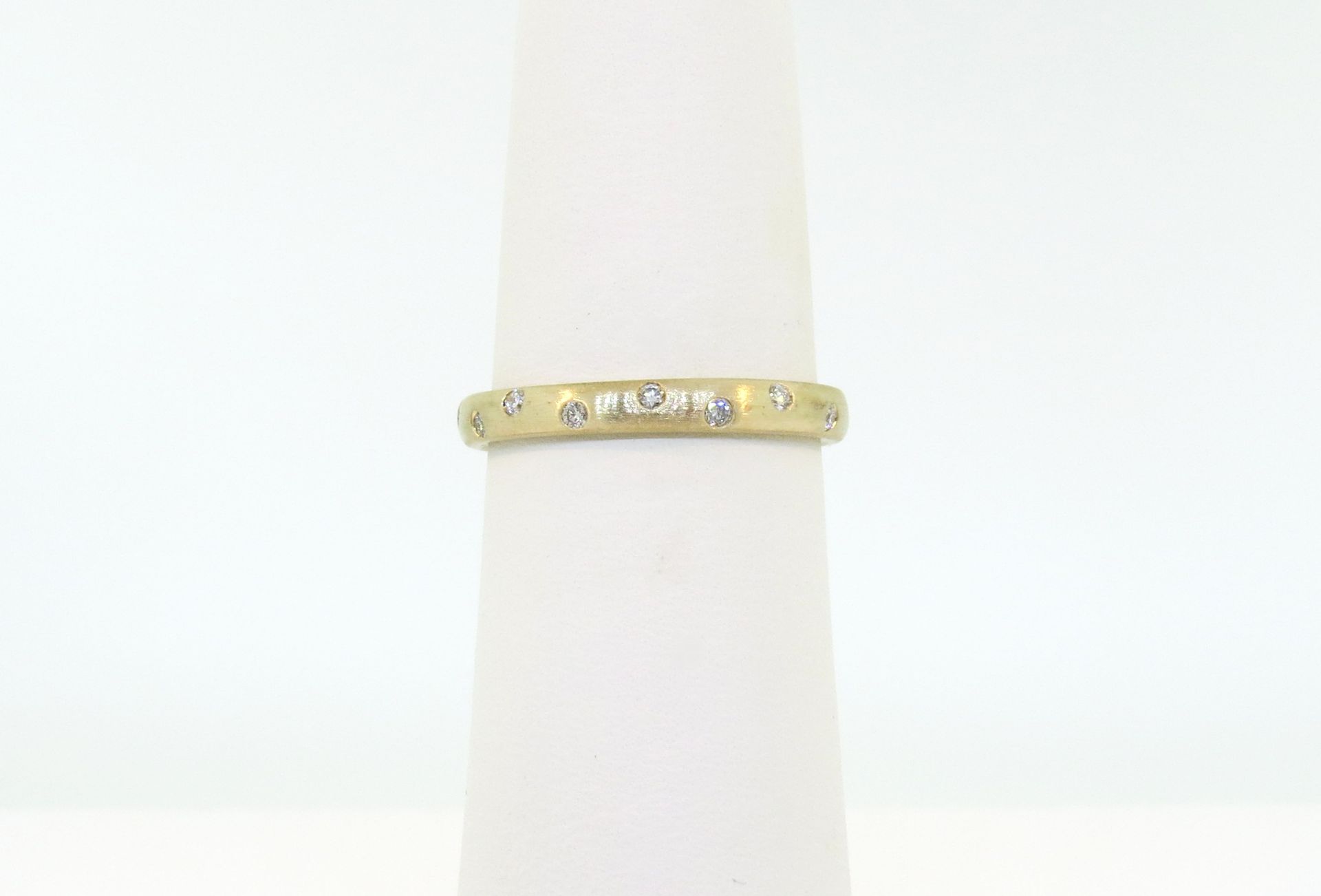 Gold ring with small diamonds on a white display stand