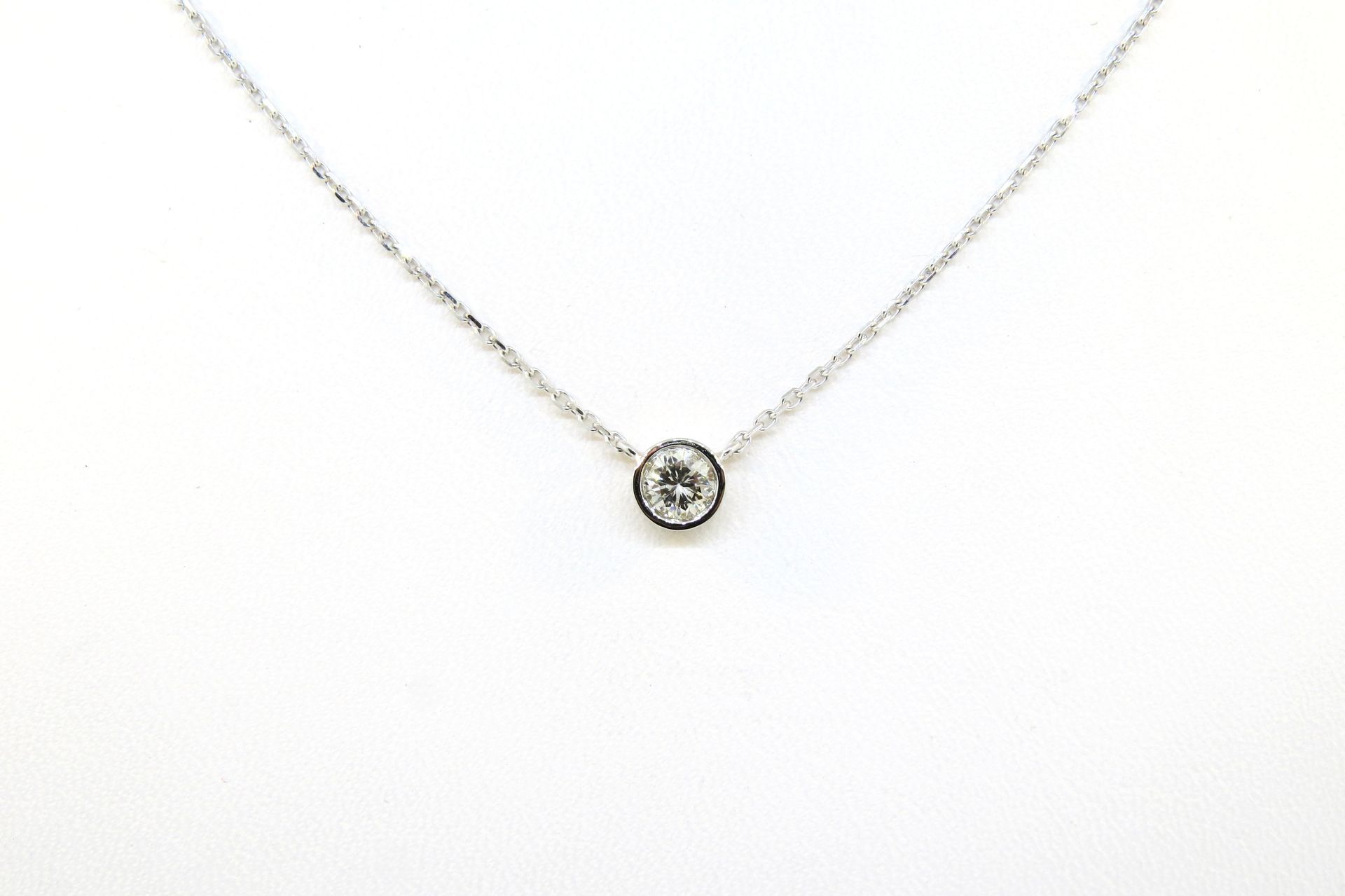 Silver necklace with a small round pendant on a white background