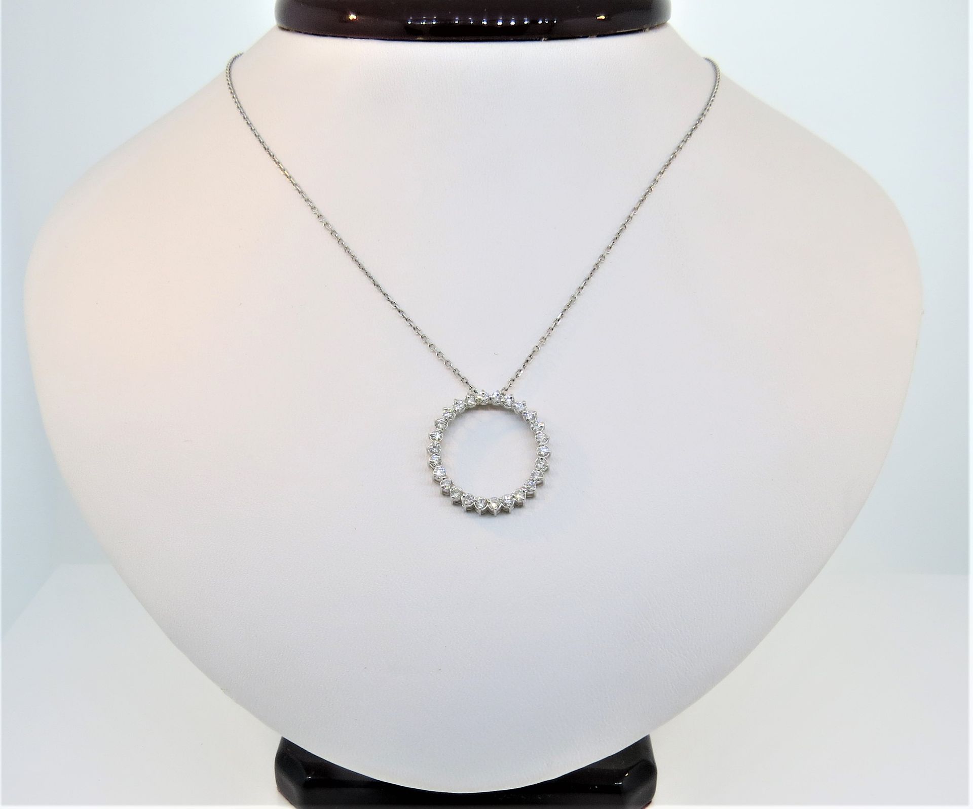 Gold beaded necklace displayed on a white bust stand with a dark wooden neck base