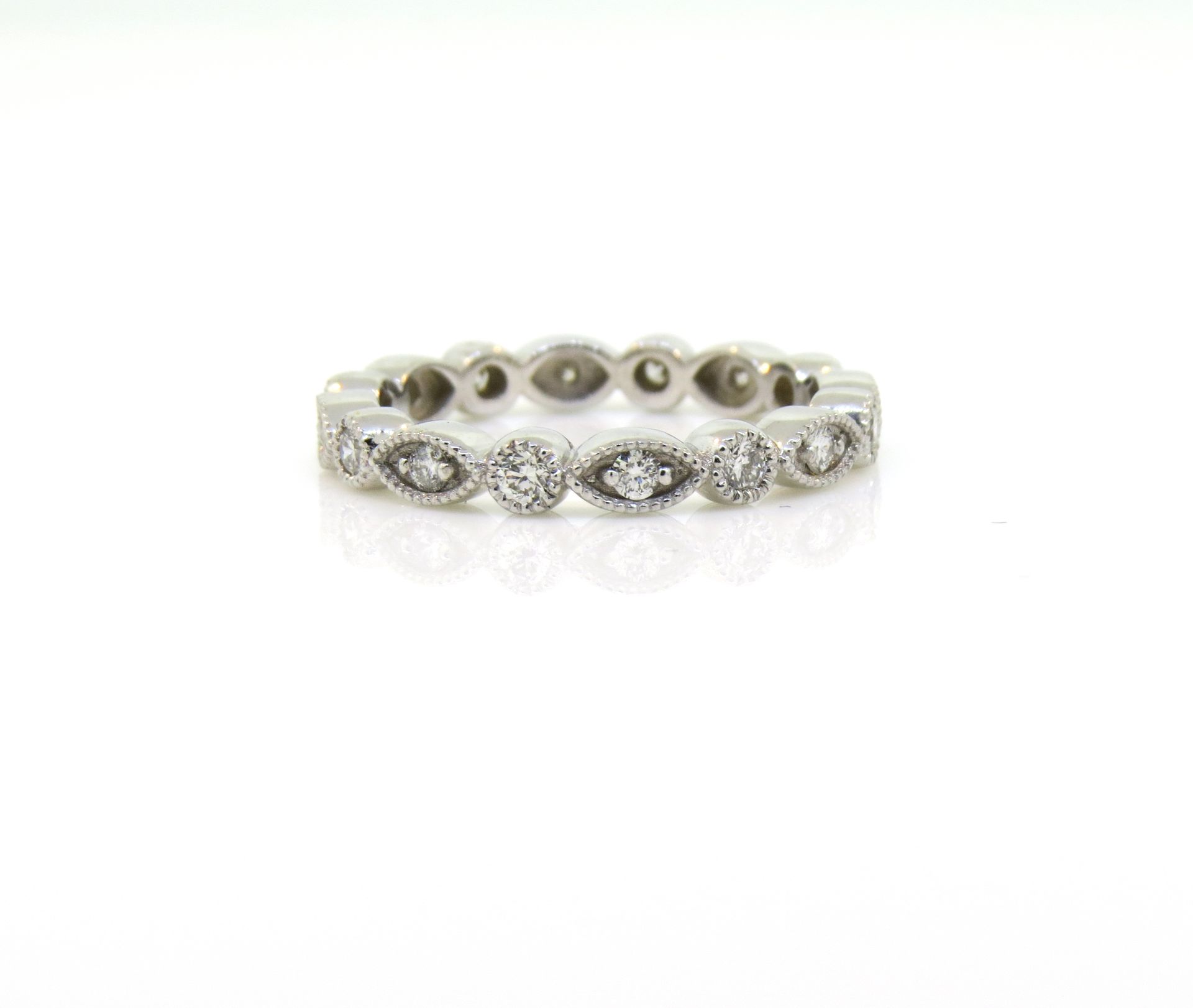 White gold ring with oval and round clear gemstones in a floral pattern
