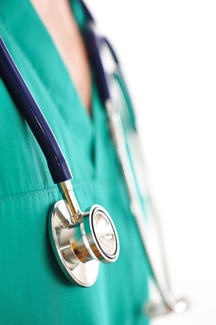 Primer plano del estetoscopio de un médico colgando sobre un uniforme quirúrgico verde.