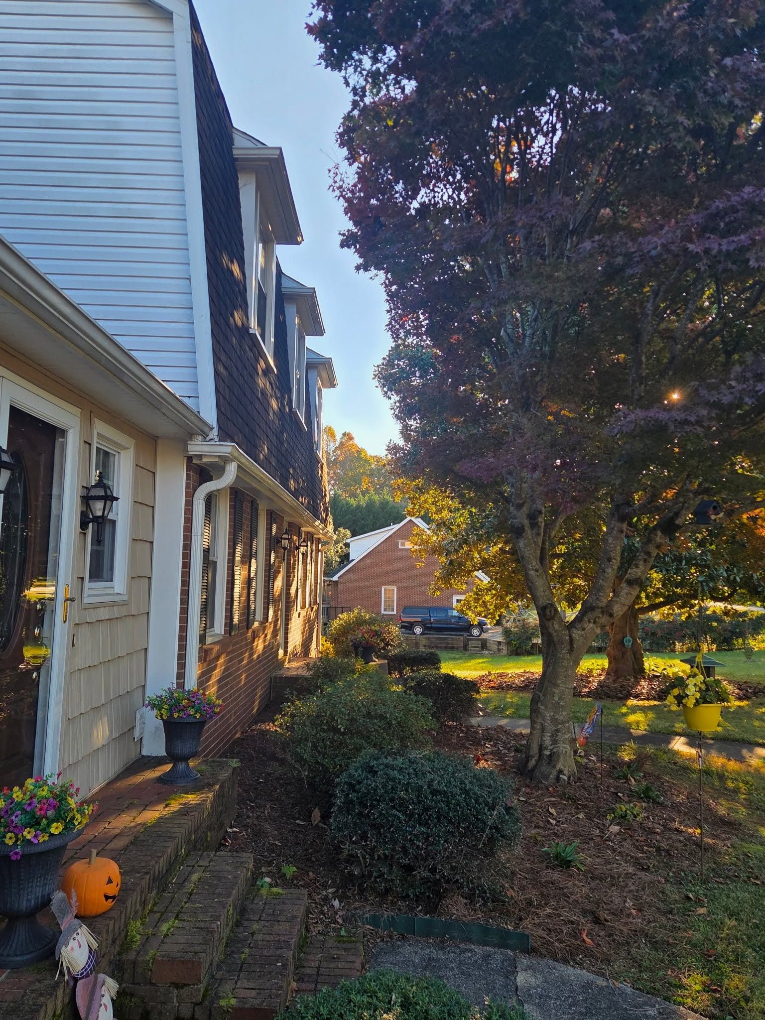 Row of townhouses with glowing porch lights beside a tree-lined garden path at dusk