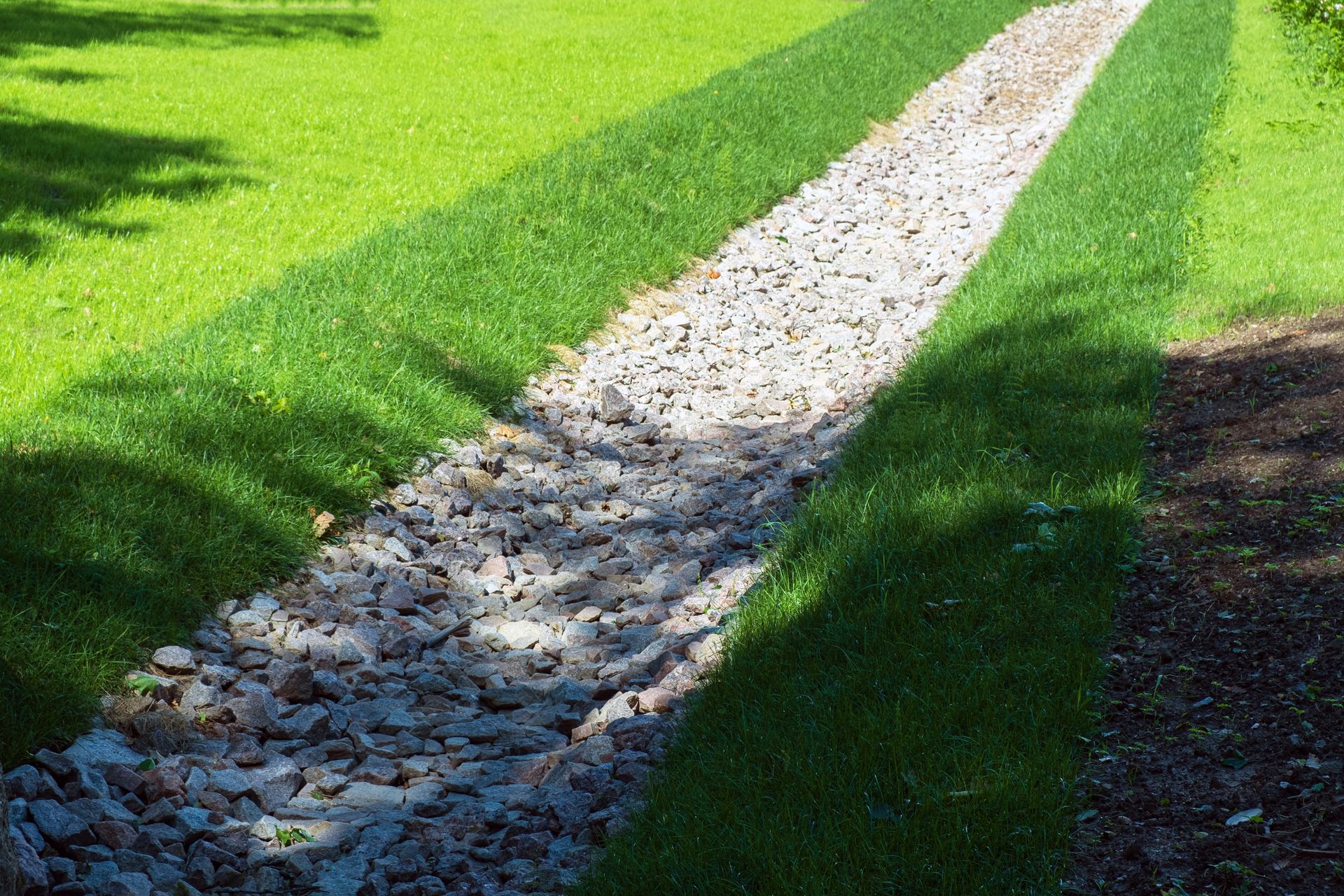 White gravel path cutting through bright green grass in sunlight