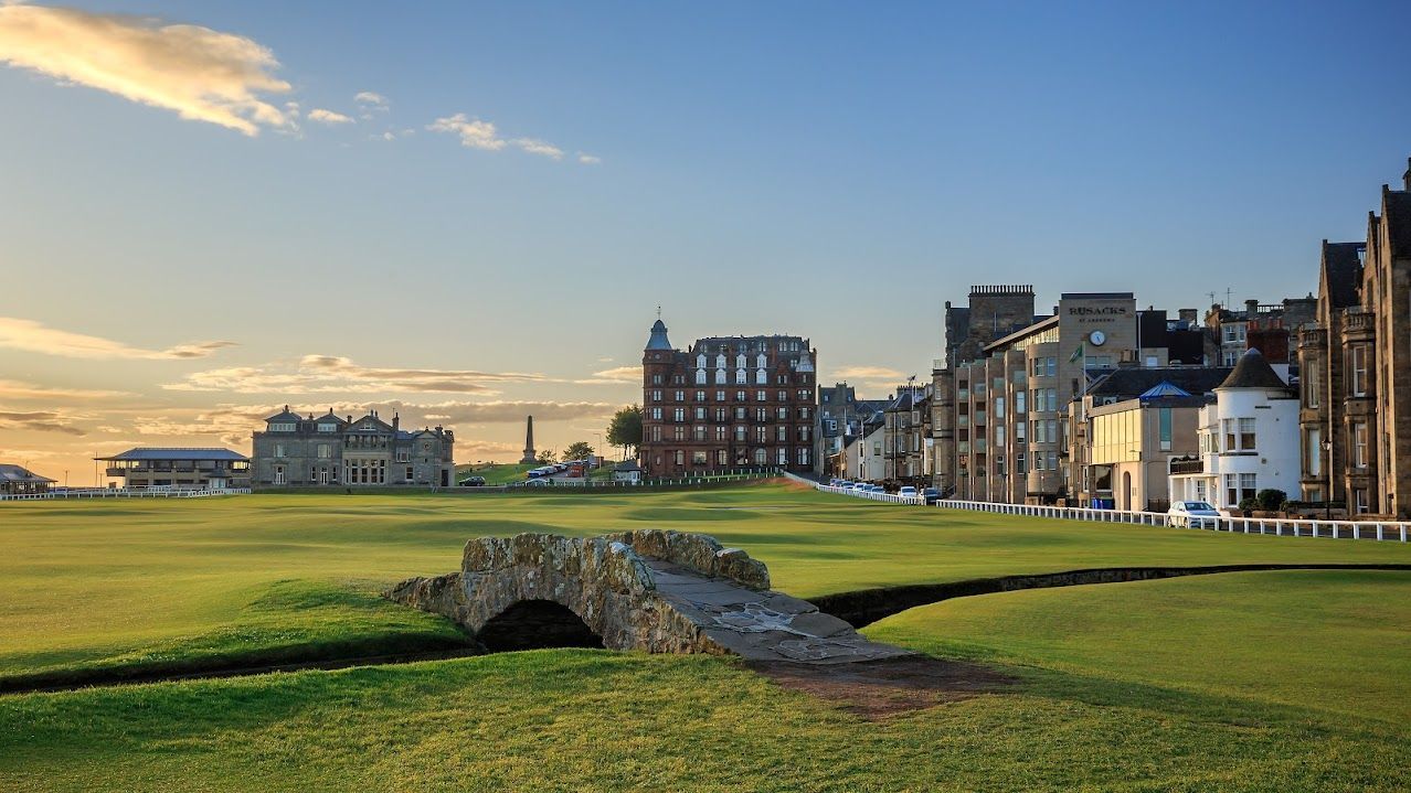 Sunset over a seaside golf course with a stone bunker and rows of buildings along the shoreline