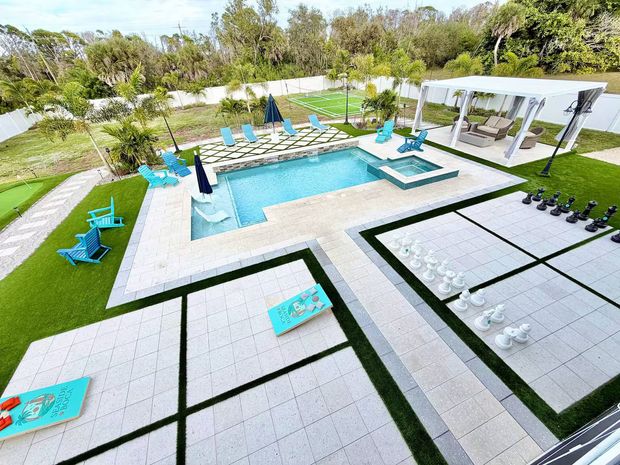 A screened-in patio containing an inground pool and a small, blue inflatable pool on a concrete deck.