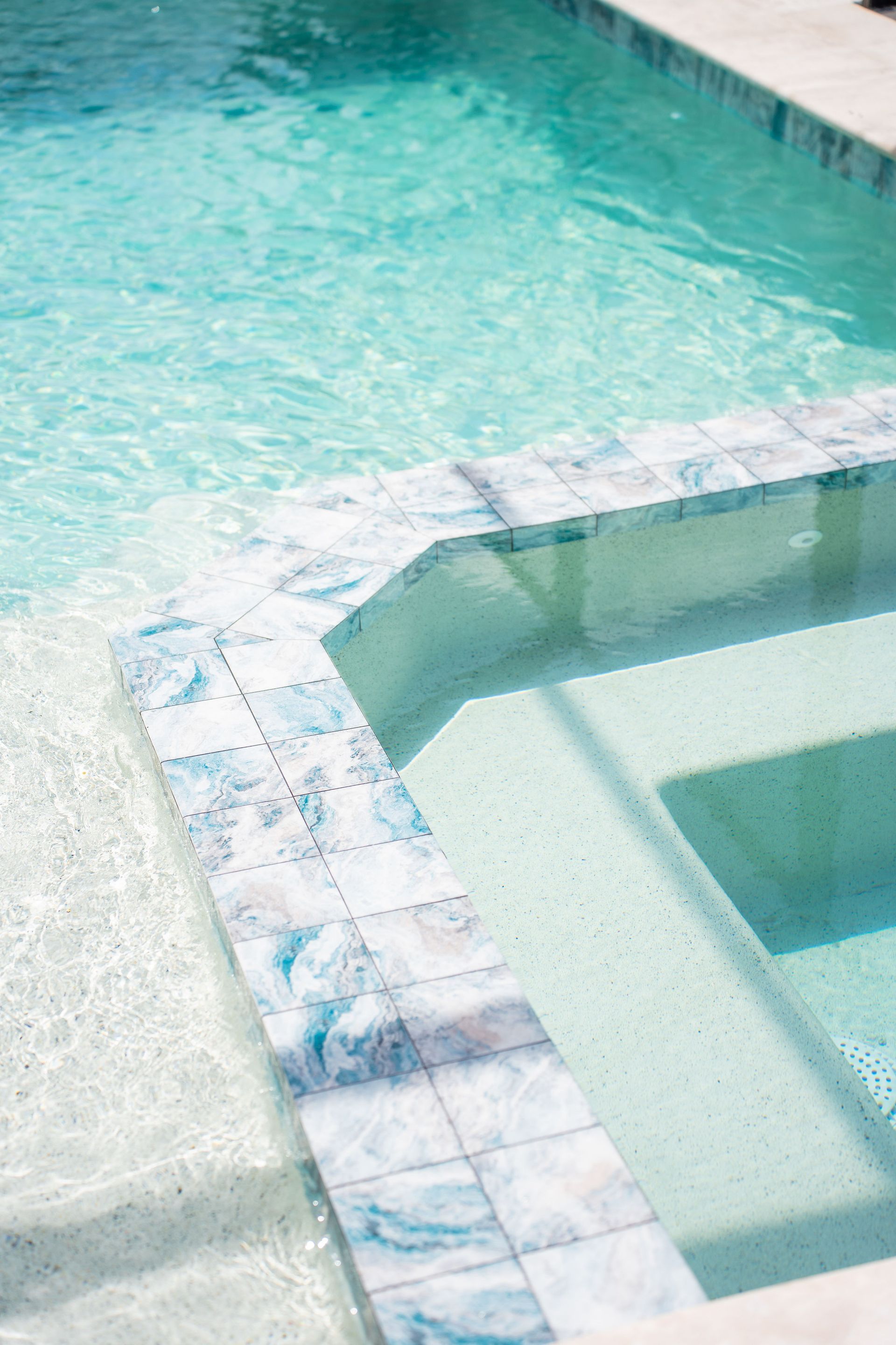 A screened-in patio containing an inground pool and a small, blue inflatable pool on a concrete deck.