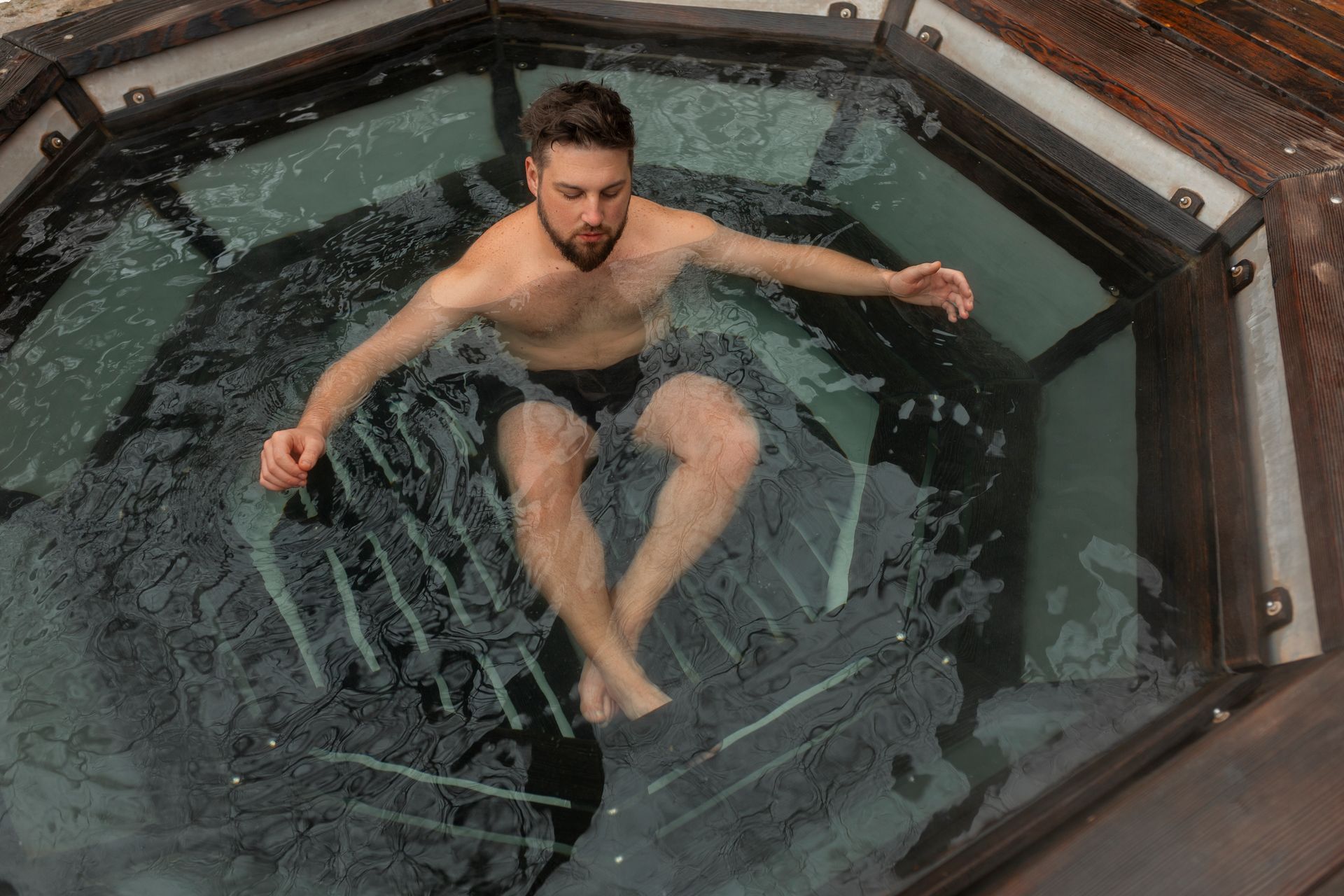 A shirtless man is floating in a hot tub.