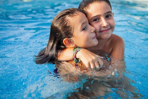 A boy and a girl are hugging in a swimming pool.
