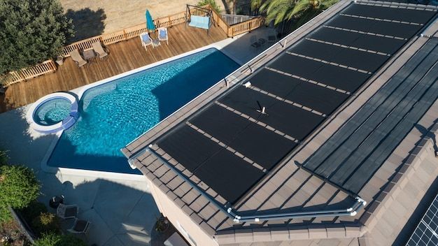 An aerial view of a house with a swimming pool and solar panels on the roof.