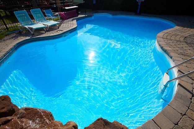A large blue swimming pool with chairs around it