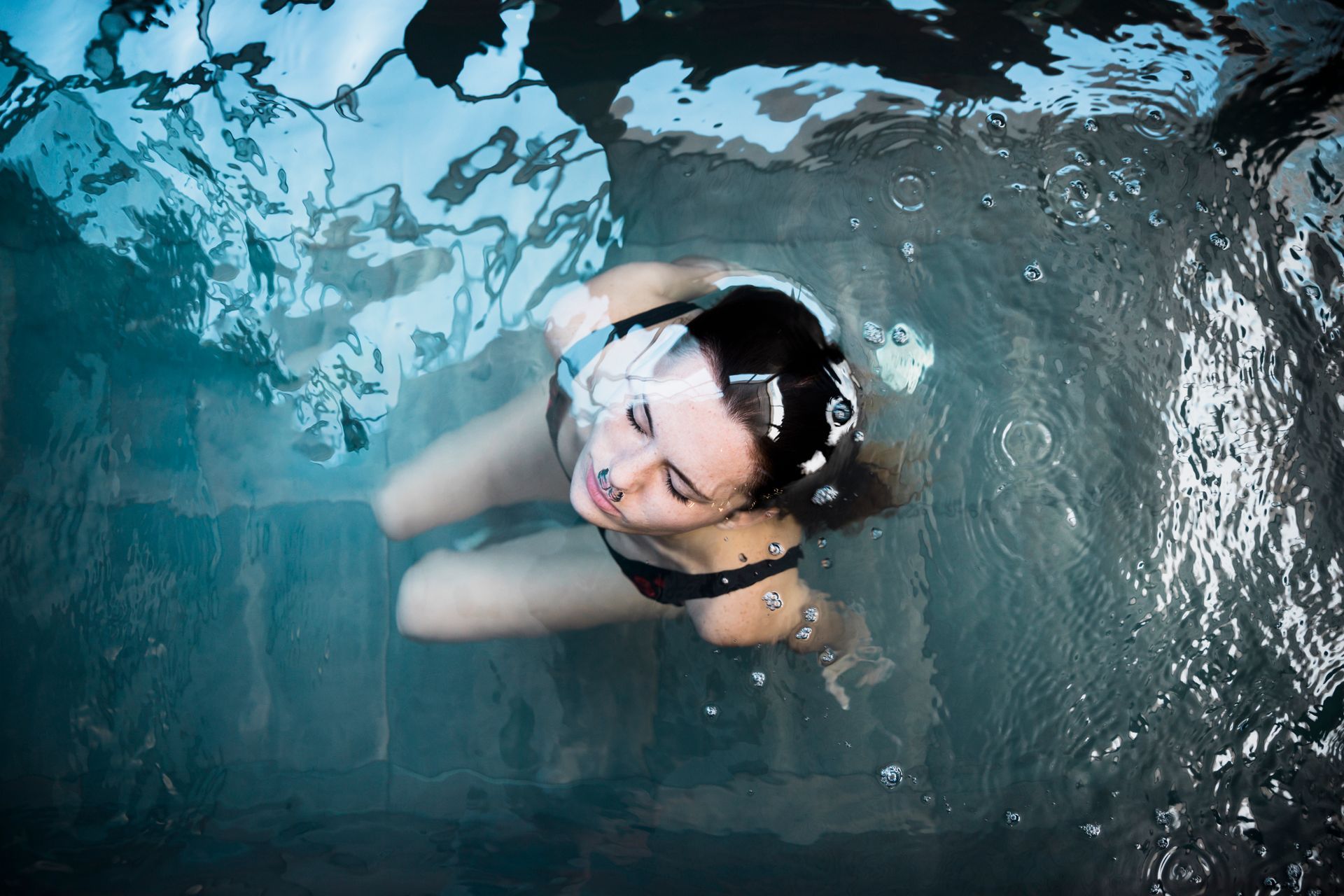 A woman in a bikini is swimming underwater in a pool.