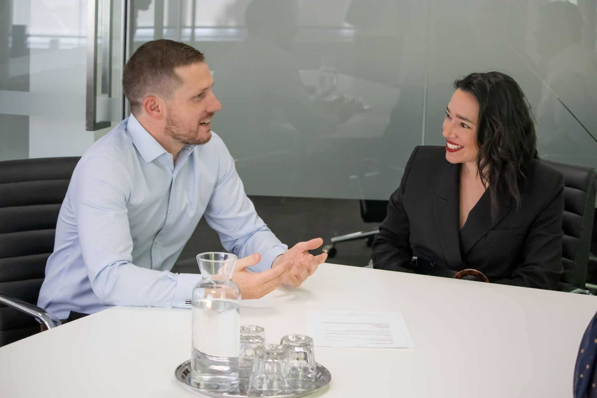 Two colleagues smiling during a business meeting at a conference table