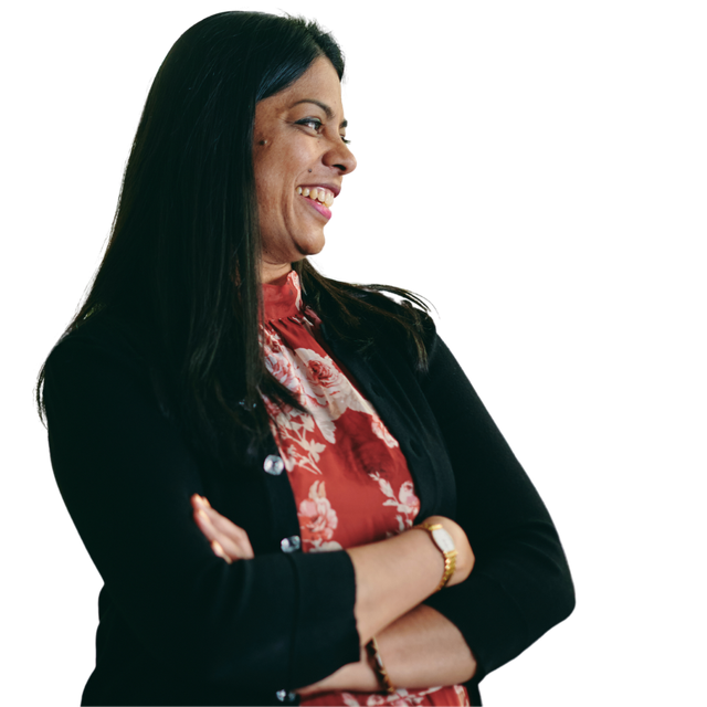 Smiling woman with long black hair, arms crossed, wearing a black blazer and red floral blouse on white background