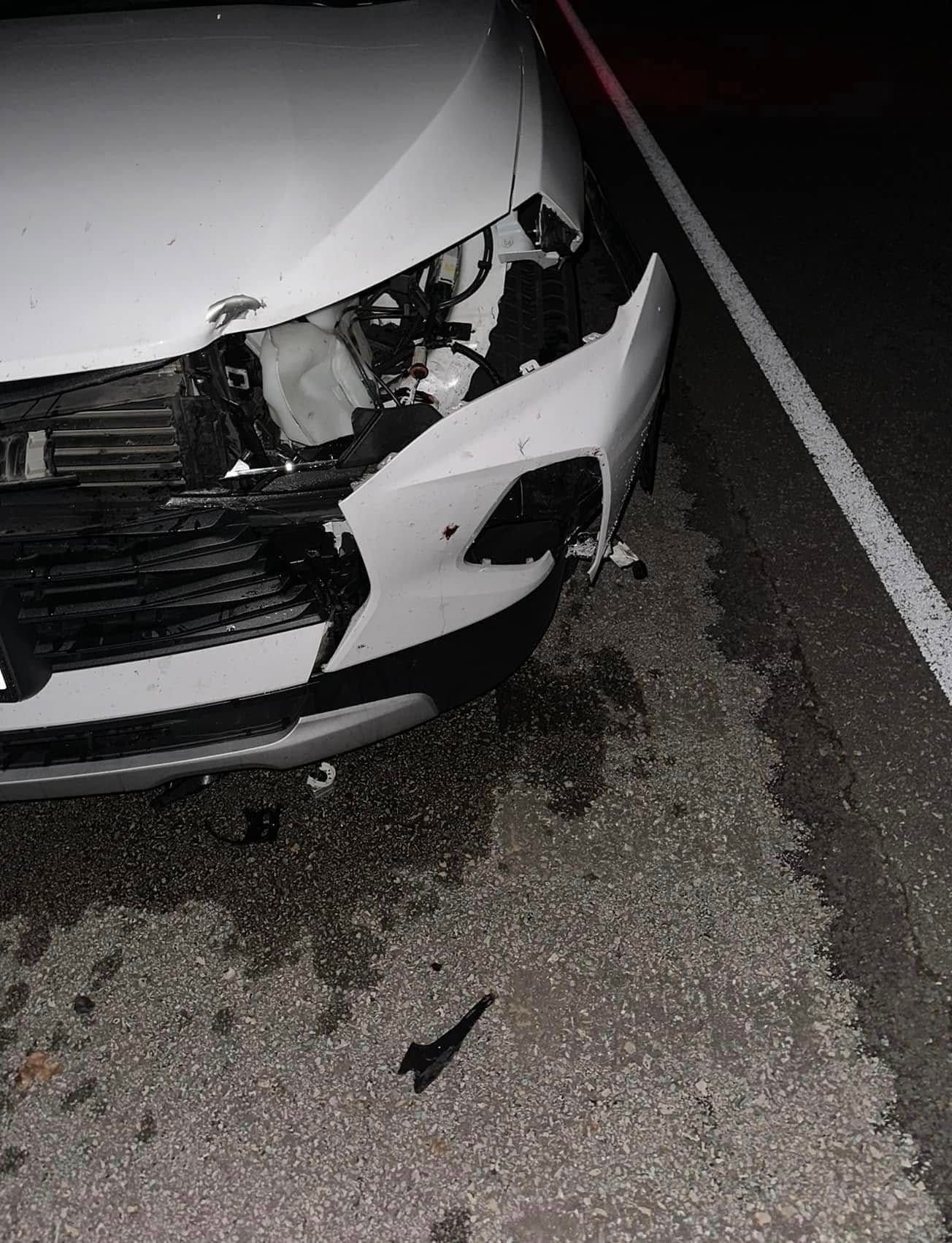 White car front bumper and headlight damaged in nighttime road crash debris on asphalt