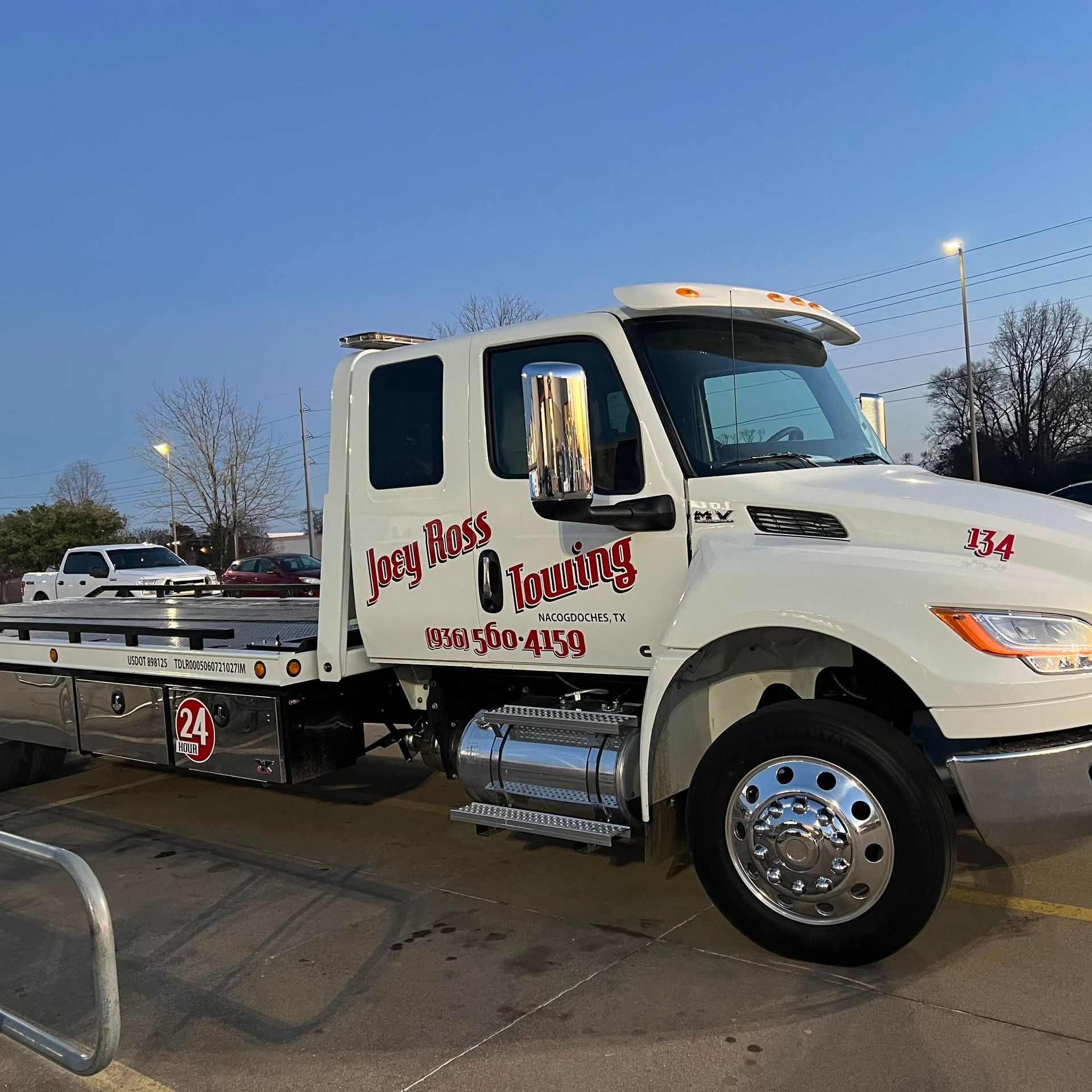 Tow truck with “Keep It Moving” logo parked outdoors at dusk