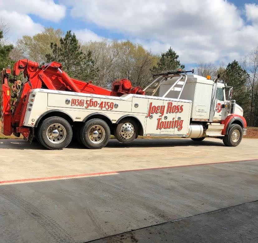 Tow truck with red crane arm parked outside, branded “Joey Ross Towing” on the side.