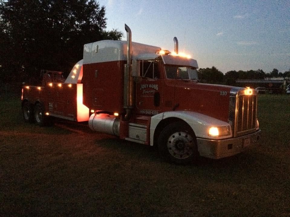 Red semi-truck with glowing lights parked outdoors at dusk