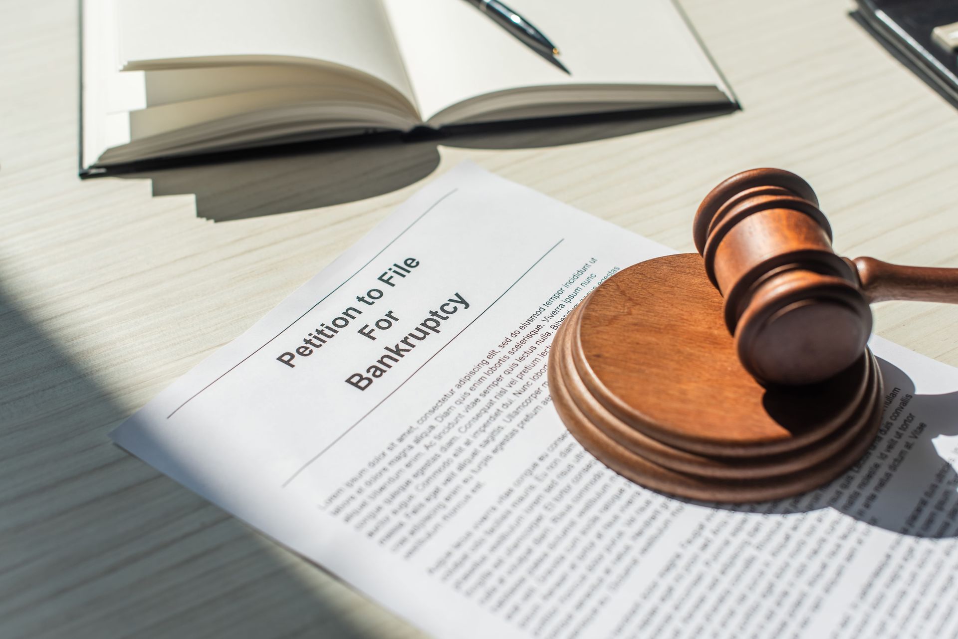 Gavel on a legal document beside an open book on a desk under sunlight