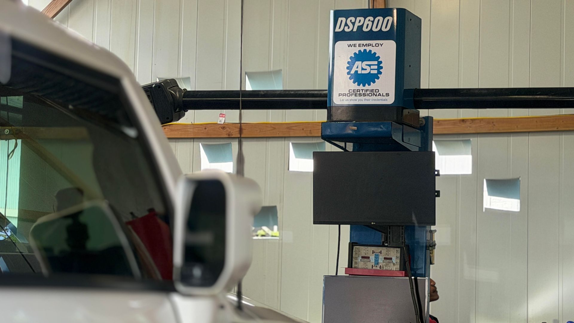 Industrial machine in a workshop, partially blocked by a white vehicle in the foreground | Sky Auto Repair