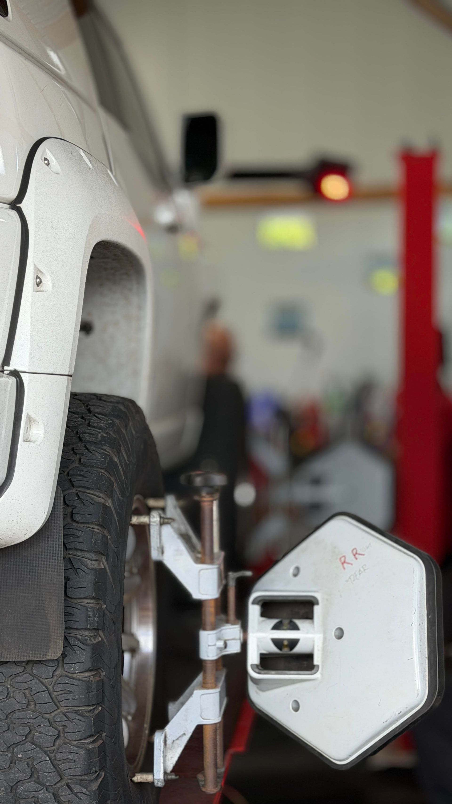 Car wheel aligned with a white measuring device in an auto repair shop interior | Sky Auto Repair