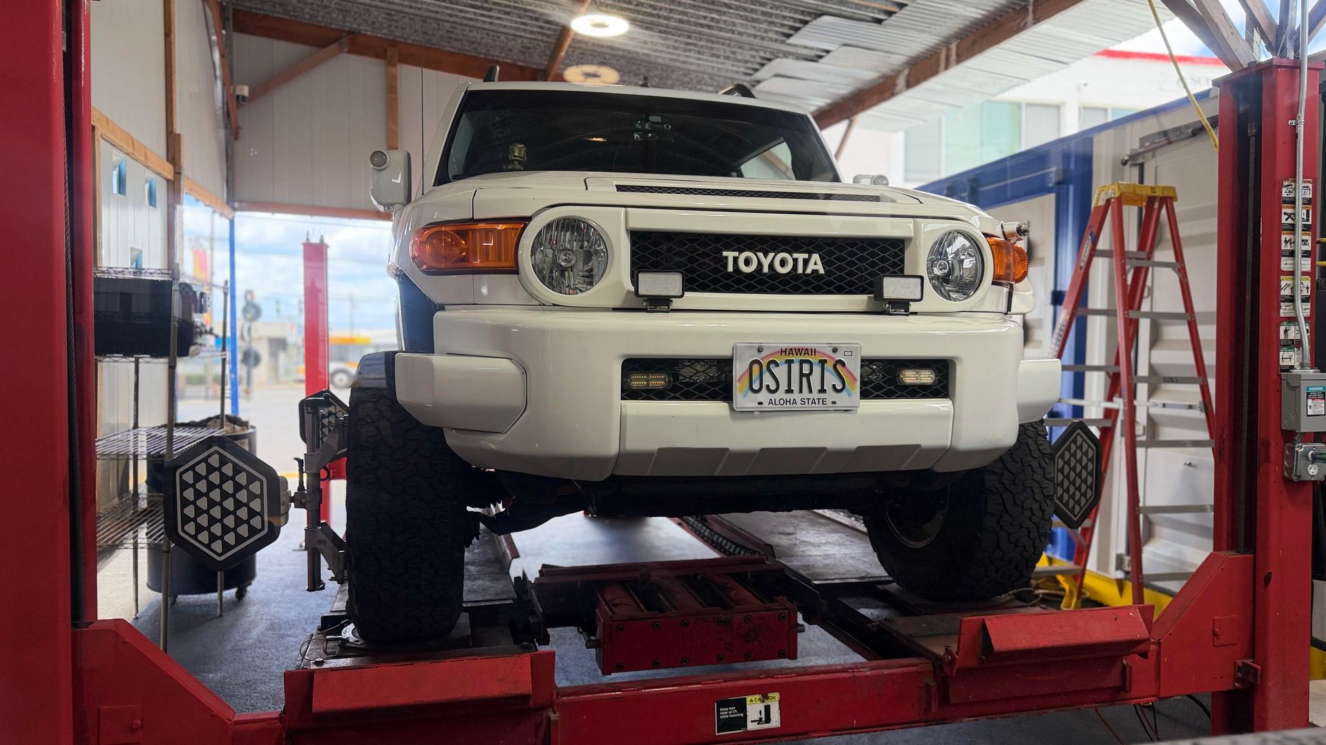 White Toyota SUV on a red car lift in an auto repair shop, seen from the front | Sky Auto Repair