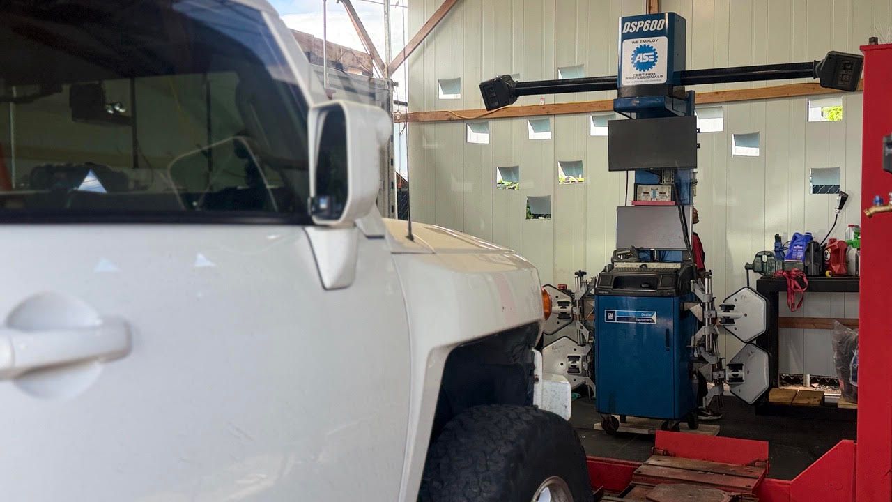 White SUV in an auto shop beside a blue tire machine and workbench with tools | Sky Auto Repair