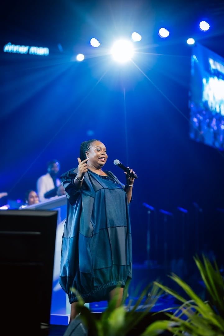 Chevelle Franklyn leading worship in a blue dress on stage at All Women Together 2026, Kigali.