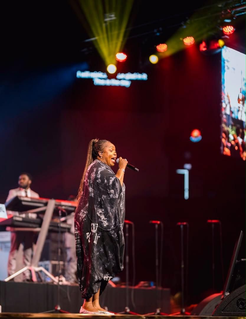 Chevelle Franklyn singing in a black dress against red stage lighting at All Women Together 2026, Kigali.